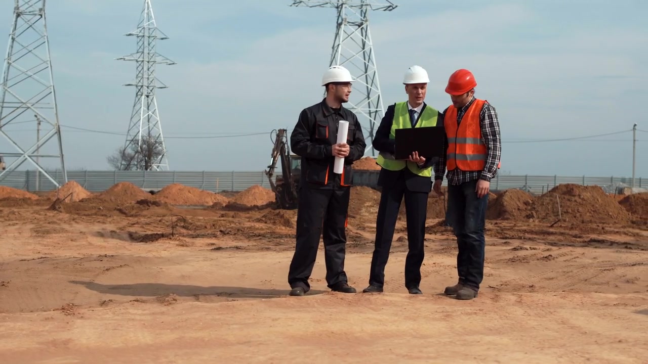 Construction managers in professional attire and safety gear reviewing plans on an active job site